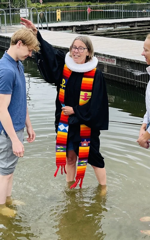 Pastorin Nicola Nehmzow tauft Ben Joel Hinz. Mit dabei: Mutter Kati Hinz. Sie stehen alle im Wasser, die Pastorin hält eine Hand über den Kopf des jungen Mannes.