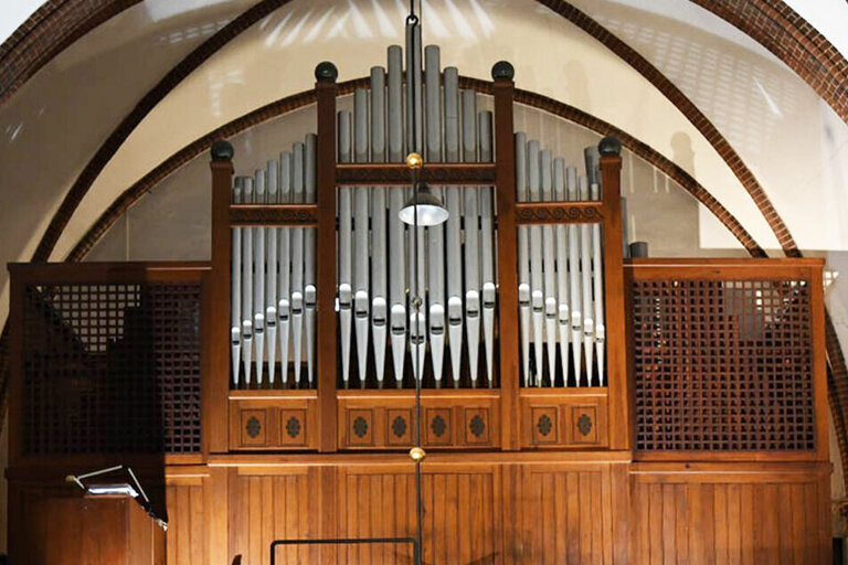 Eine Orgel mit braunem Holz. Die Pfeifen ragen in der Mitte in die Höhe