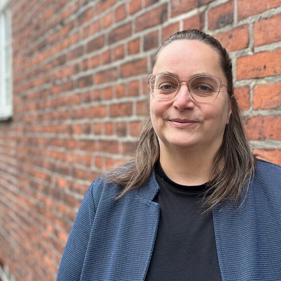 Junge Frau vor einem Backsteingebäude