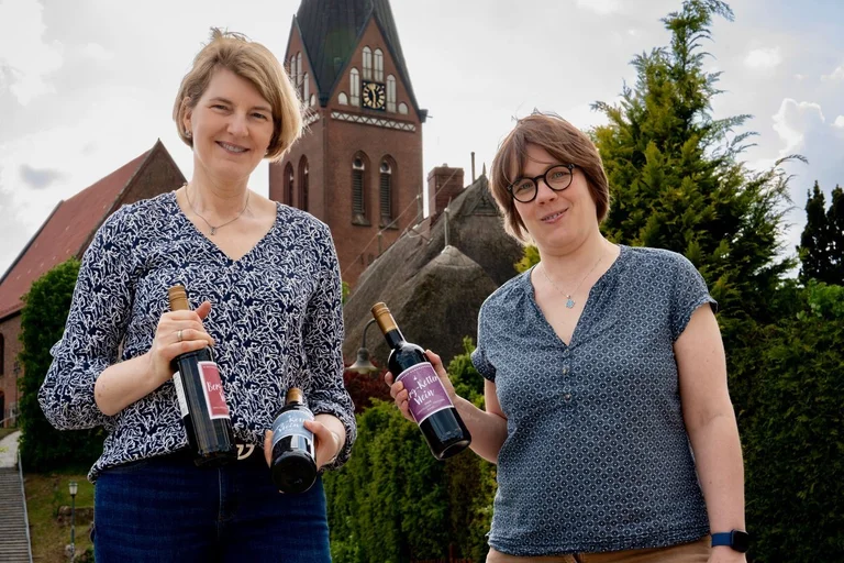 Zwei Menschen mit Flaschen vor einer Kirche 