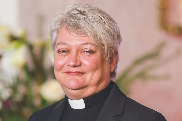 Eine Pastorin schaut lächelnd in die Kamera.