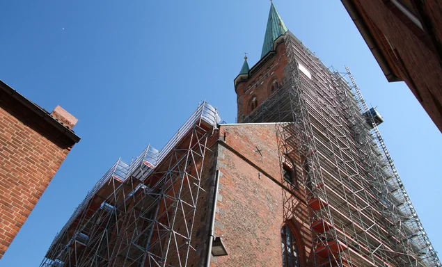 Eine große Kirche ist mit einem Baugerüst eingerüstet. Der Himmel ist strahlend blau.