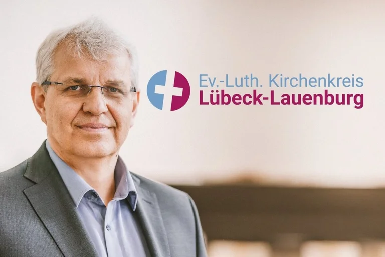 Ein Mann schaut in die Kamera. Neben ihm befindet sich ein Logo.