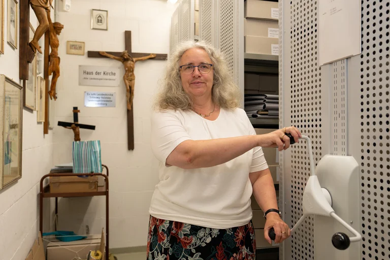 Eine Frau steht in einem Raum und Schautb in die Kamera