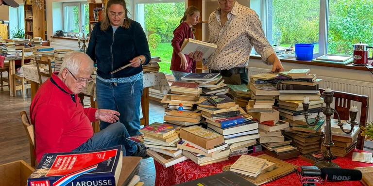 Mehrere Menschen inmitten von Büchern in einem Raum.