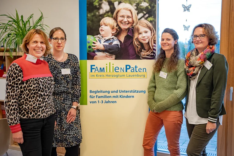 Vier Frauen stehen vor einem Plakat