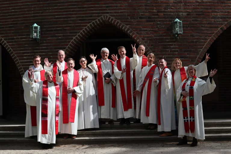 Gruppenfoto mit vielen Pastorinnen und Pastoren vor einer Kirche.