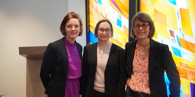 Drei Frauen stehen nebeneinander und lächeln in die Kamera.