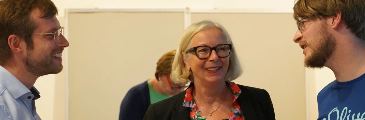 Eine Frau spricht lachend mit zwei Männern.