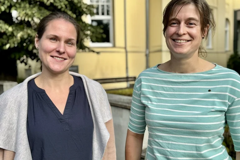 Zwei Personen lächeln in die Kamera