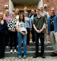 Eine Gruppe junger Menschen steht auf einer Treppe für ein Gruppenfoto zusammen.
