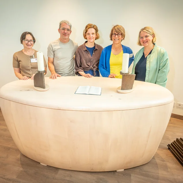 Gruppe an Menschen steht hinter dem neuen Altar im Raum der Stille