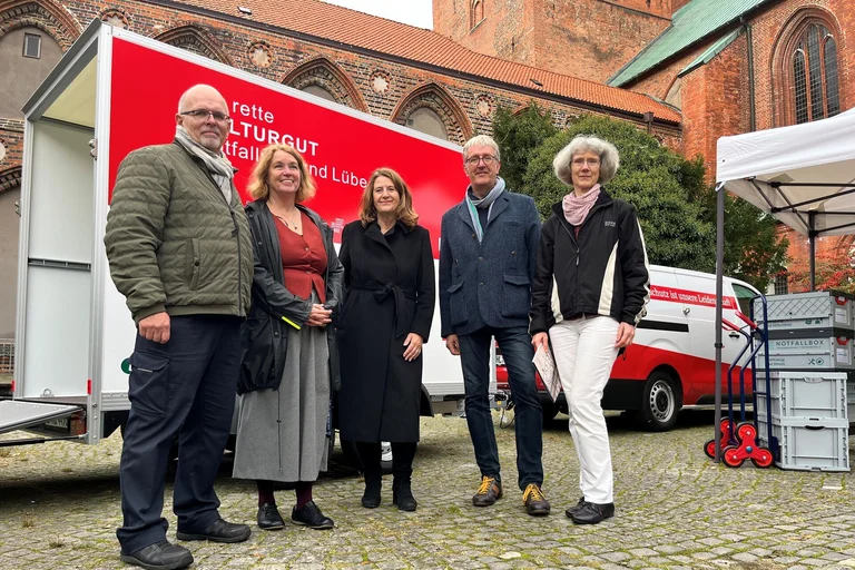 Fünf Menschen stehen vor einem großen Autoanhänger