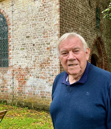 Ein älterer Mann vor einer Kirche