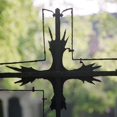 Schwarzes, verwittertes Kreuz von grünem Hintergrund