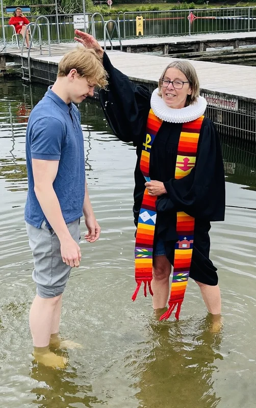 Pastorin Nicola Nehmzow tauft Ben Joel Hinz. Mit dabei: Mutter Kati Hinz. Sie stehen alle im Wasser, die Pastorin hält eine Hand über den Kopf des jungen Mannes.