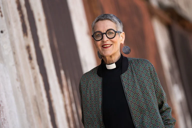 Eine Frau im Collarhemd und mit schwarzer Brille lächelt in die Kamera