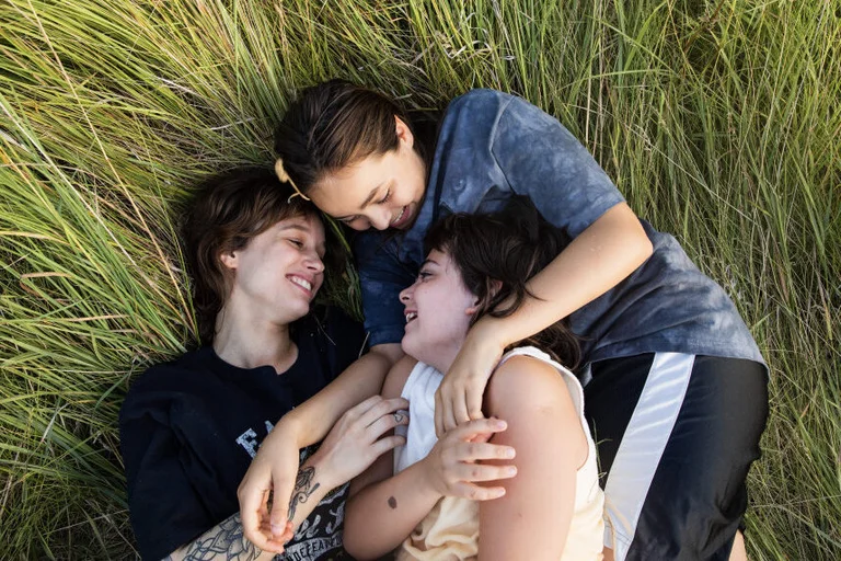 Drei Kinder liegen auf einer Wiese