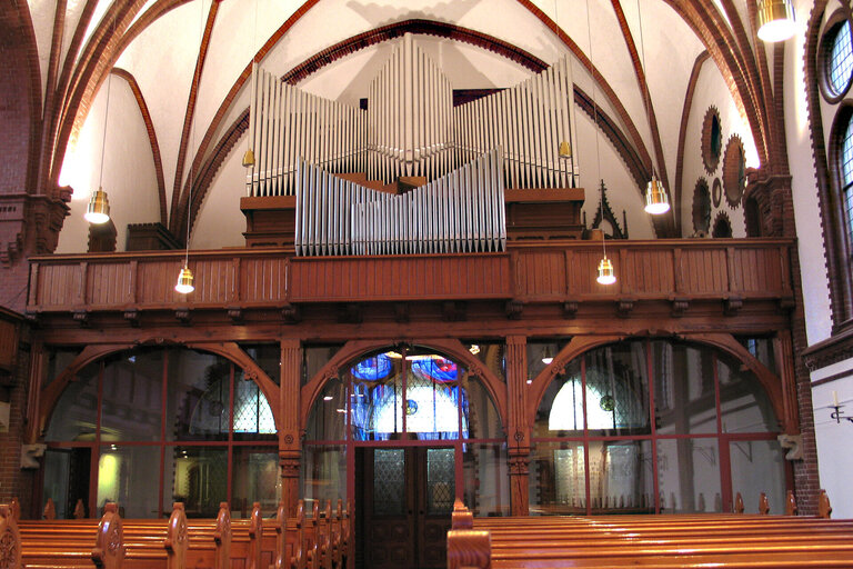 Der Innenraum einer Kirche mit Holzbänken und einer Orgel auf der Empore