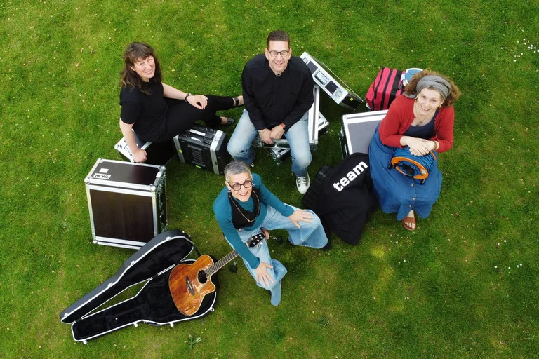 Menschen sitzen mit Kisten auf einem Rasen