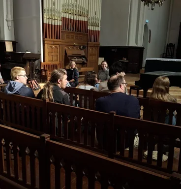 Junge Menschen sitzen auf Kirchenbänken in eienr Kirche.