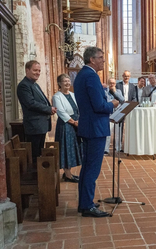 Menschen stehen in einer Kirche an Stehstischen
