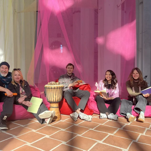 Mehrere Personen sitzen auf bunten Sitzsäcken und vor bunten Tüchern in einer Kirche.