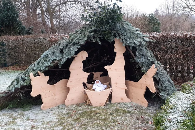 Maria und Josef mit den Tieren und dem Kind in den Windeln aus Holz gearbeitet auf dem Rasen stehend.