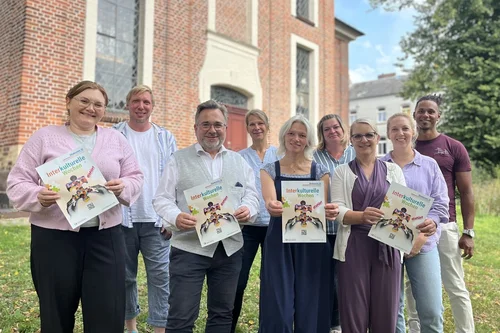 Gruppenfoto mit Frauen und Männern. Einige halten Plakate der Interkulturellen Wochen. 
