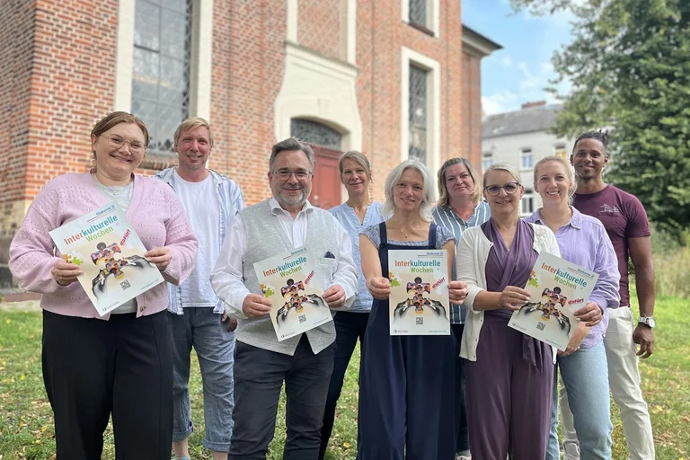 Gruppenfoto mit Frauen und Männern. Einige halten Plakate der Interkulturellen Wochen. 