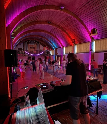 Kirchenschiff mit Partybeleuchtung, DJ und Tanzenden