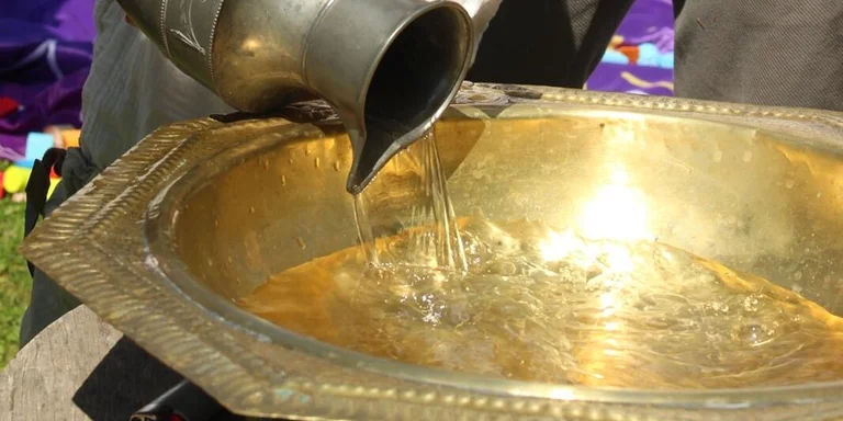 Junge gießt Wasser in die Taufschale