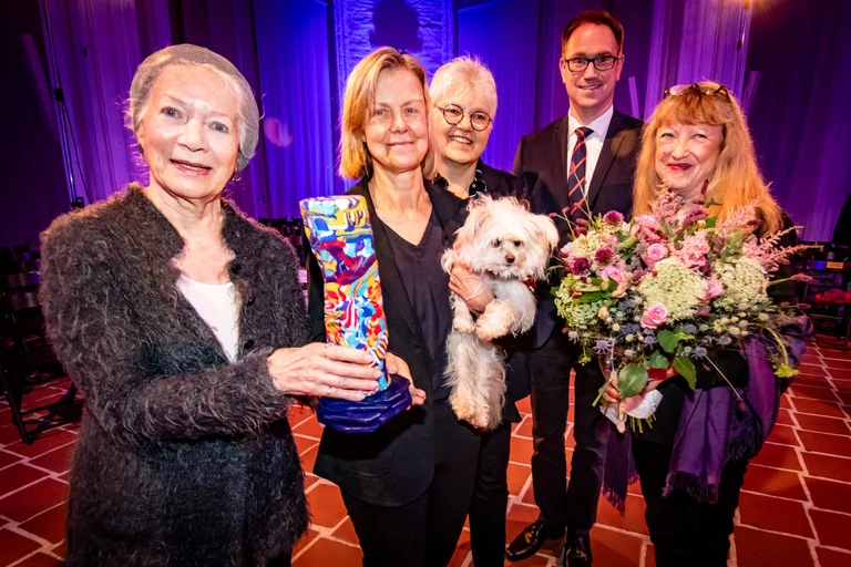 Personen stehen mit einer Skulptur und einem Hund in einer Kirche