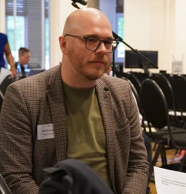 Ein Mann spricht mit einer anderen Personen die man nur von hinten sieht.