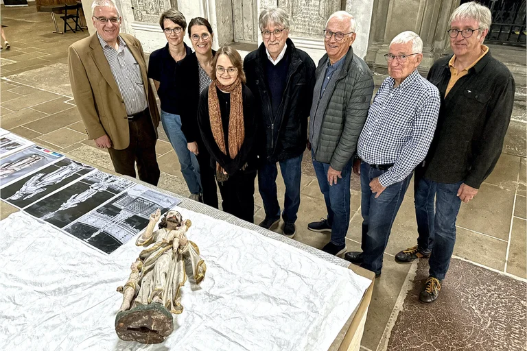 Gruppenfoto vor einem Tisch mit Fotos und einer liegenden Jesus-Figur.