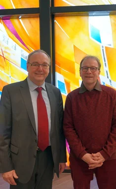 Zwei Männer stehen nebenander und lächeln in die Kamera.