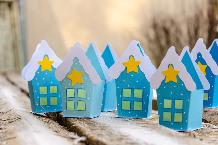 Hellblaue Papierhäuser, jedes mit einem gelben Stern
