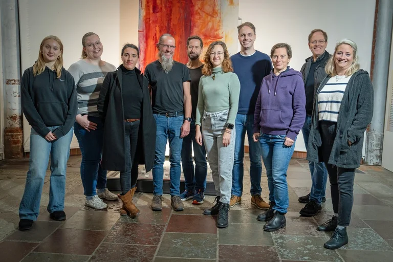 Mehrere Personen stehen als Gruppe in einem Kirchraum.