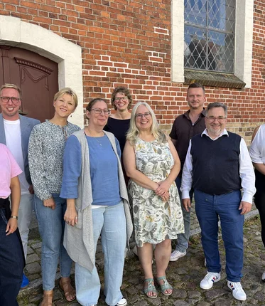 Neun Frauen und Männer stehen für ein Gruppenbild zusammen