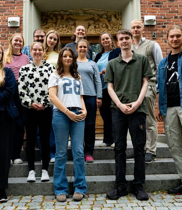 Eine Gruppe junger Menschen steht auf einer Treppe für ein Gruppenfoto zusammen.