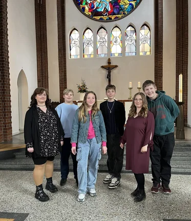 Sechs junge Menschen stehen im Altarraum einer Kirche.