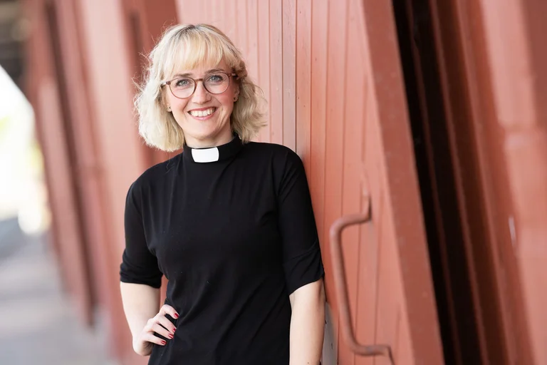 Eine Frau steht an einer roten Wand 