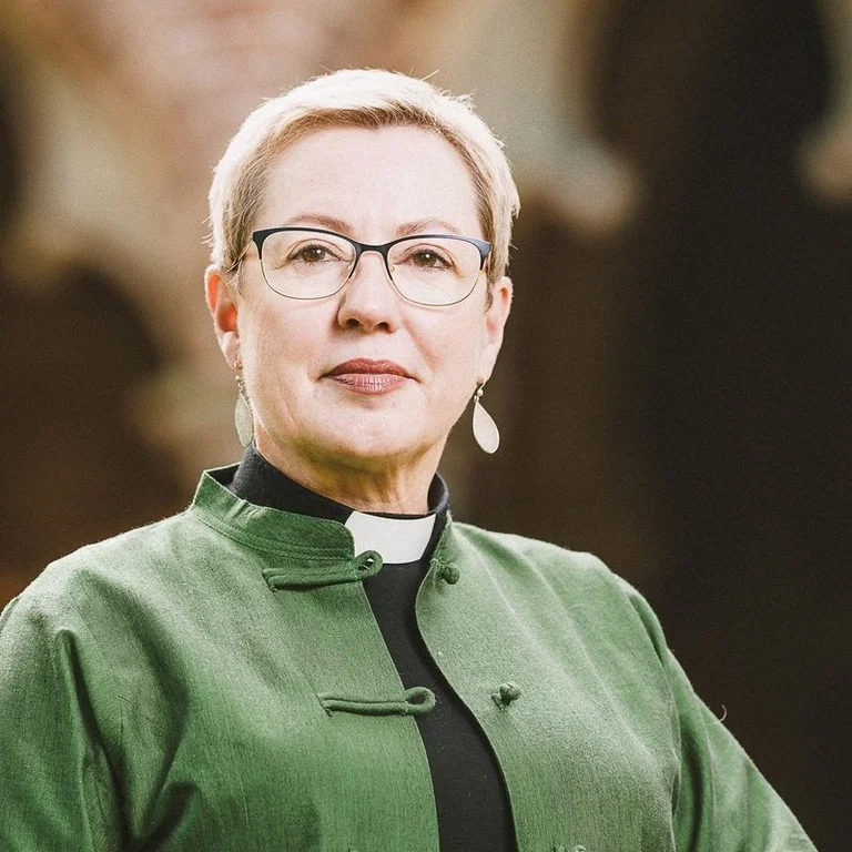 Eine Frau mit kurzen Haaren blickt ernst in die Kamera.