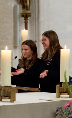 Zwei junge Frauen stehen an einem Altar
