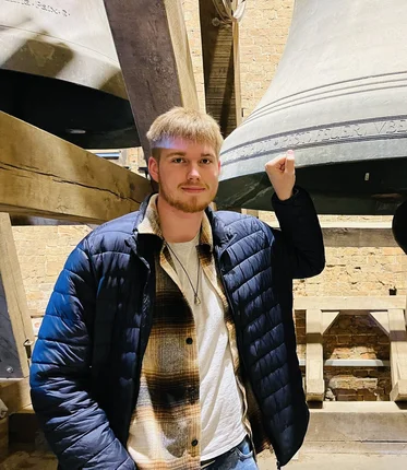 Ein junger Mann steht vor der großen Glocke der Marienkirche.