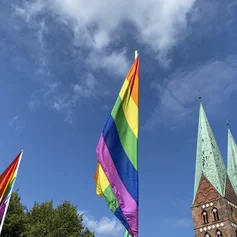 Eine Regenbogenflagge und ein Kirchturm