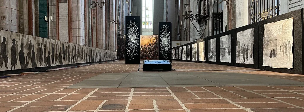 Einblick in die Ausstellung: Zur rechten und linken Seite sind Wände mit Bildern aufgestellt.