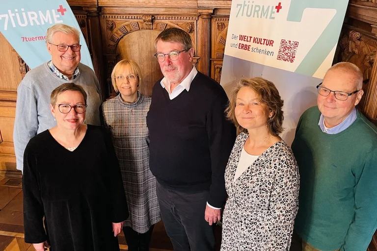 Eine Frau und zwei Männer der Wessel Stiftungen stehen mit der Pröpstin Petra Kallies und Referentin Heike Reimann von 7Türme+ vor einem Rollup und einer Beachflag des Projektes. 