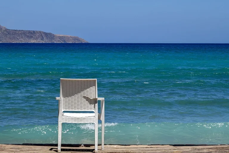 Weißer Stuhl am Strand mit Blick auf das blaue Meer