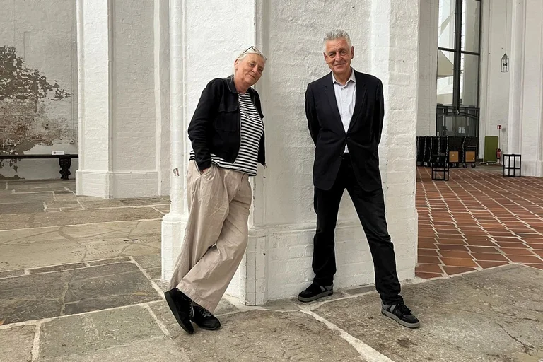 Eine Frau und ein Mann lehnen an einer weißen Säule in einer Kirche.